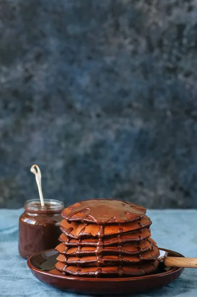 Schokoladen-Pfannkuchen mit Sirup in einem Teller auf blauem Hintergrund. c — Stockfoto