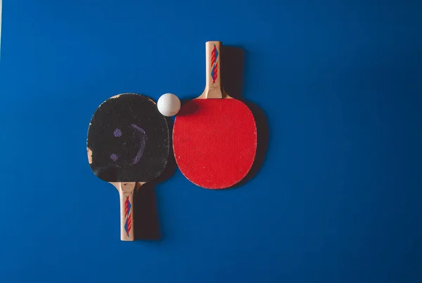 Two fryed tennis rackets on a blue tennis table background.
