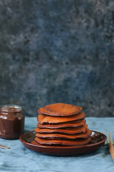 Шоколадные блинчики с сиропом в тарелке на синем фоне . — стоковое фото