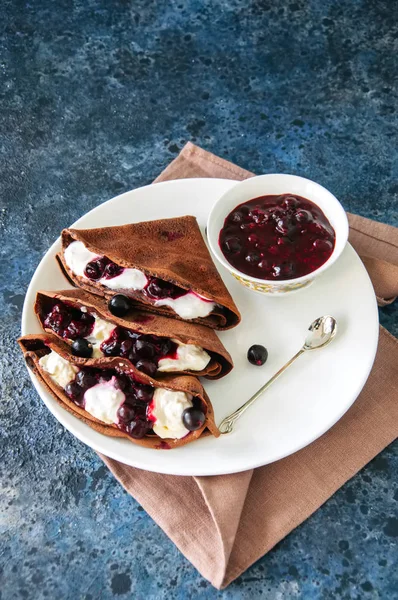 Chocolate crepes (blinis) with sour cream and black currant sauc