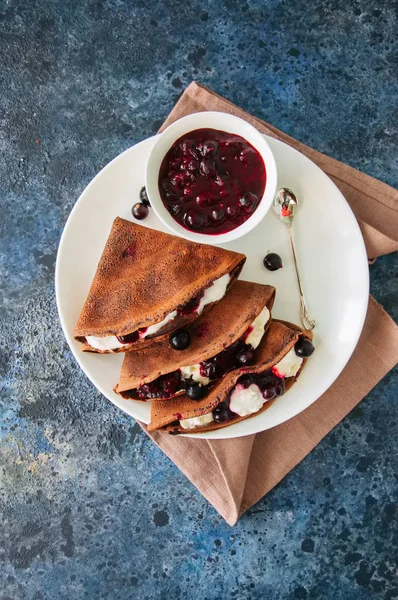 Chocolate crepes (blinis) with sour cream and black currant sauc