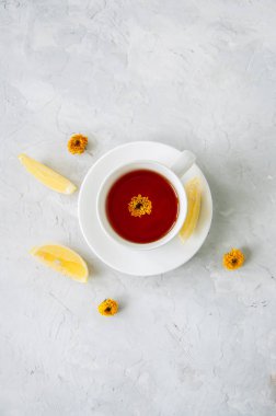 Bir fincan çiçek çay, limon dilimleri ve bir beyaz üzerine kuru çiçekler