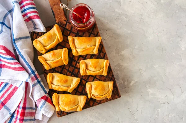 Two types of empanadas on a wooden plate with ketchup