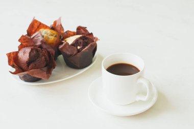 Bir fincan kahve ve beyaz arka planda üç kek..