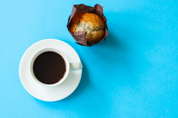Чашка кофе и шоколадный кекс на голубом фоне . — стоковое фото
