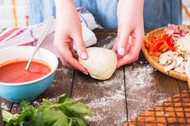 Kadın ellerinde çiğ hamur, domates sosu, yemek malzemesi.