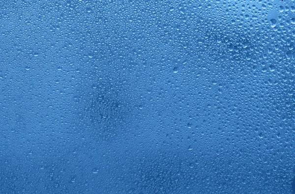 Okno z kroplami wody. Niebieskie tło kolorowe. — Zdjęcie stockowe
