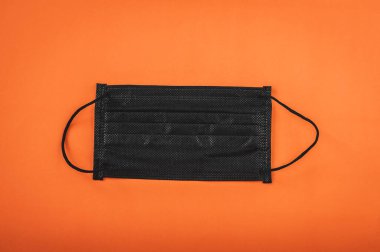 Turuncu arka planda siyah renkli tıbbi maske.