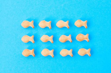 Mavi arka planda çıtır balık krakerleri. Sürü sembolü konsepti.