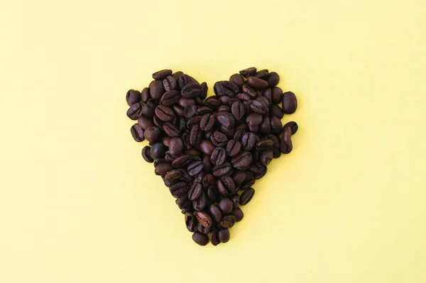 Pieczone Ziarna Kawy Żółtym Tle Widok Góry Symbol Kształcie Serca — Zdjęcie stockowe
