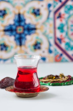 Bardakta Türk çayı, beyaz arka planda Müslüman boncukları. Kapat..