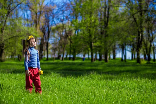 Menina em uma grama verde em uma grinalda de flores na primavera — Fotografia de Stock