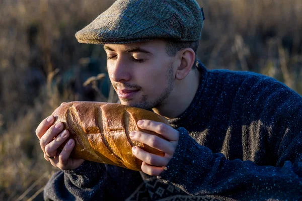 Молодой парень нюхает свежий хлеб на открытом воздухе — стоковое фото