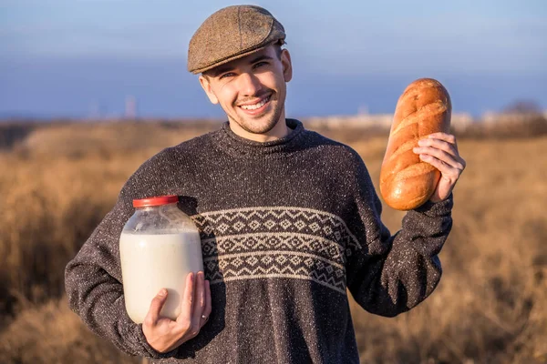 Счастливый человек с хлебом и молоком в поле — стоковое фото