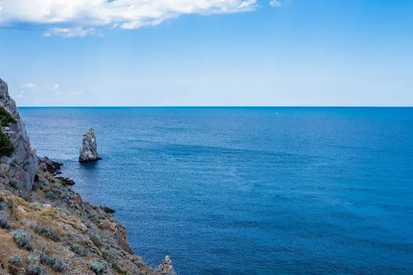 Кусок скальных гор в море с голубым небом на заднем плане — стоковое фото