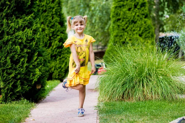 Glad liten flicka på ett grönt gräs — Stockfoto