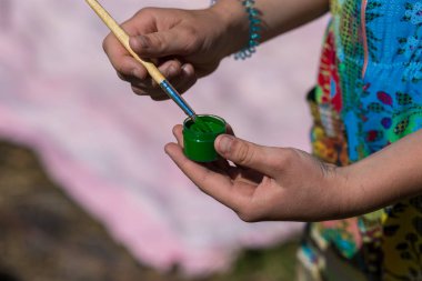 Bir çocuk turuncu bir boya ve fırça elinde tutuyor