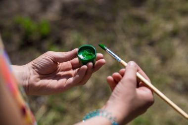 Bir çocuk turuncu bir boya ve fırça elinde tutuyor