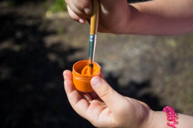 Bir kız bir yeşil boya ve fırça elinde tutuyor