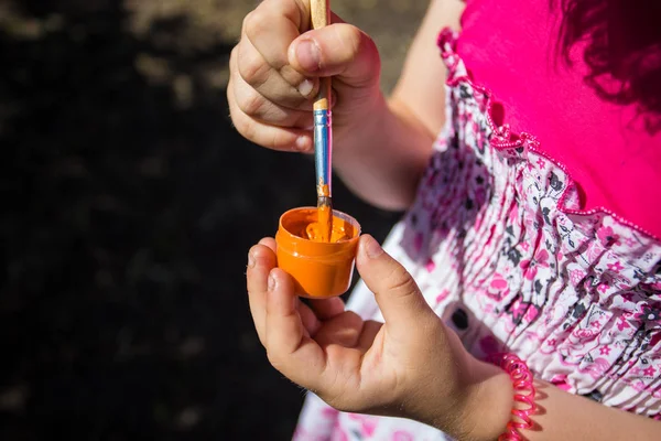 Bir kız bir yeşil boya ve fırça elinde tutuyor