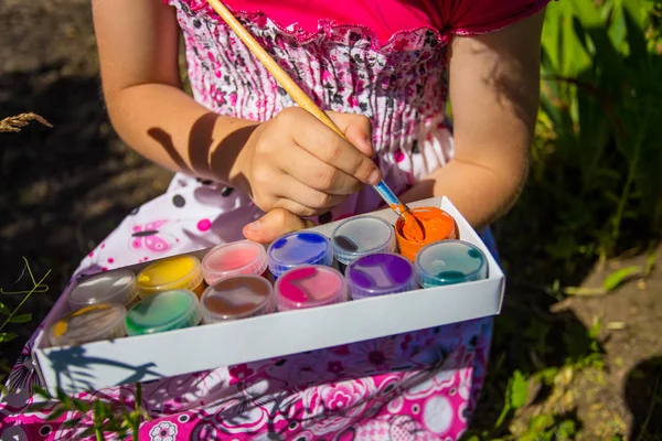 Aranyos kis lány játszik festékek rajz. Színek, a természet. — Stock Fotó