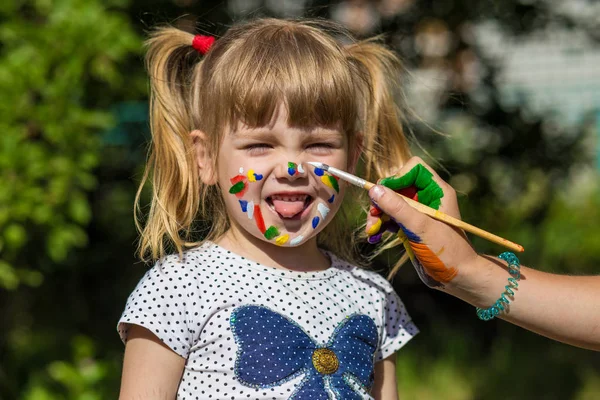 Chica linda alegre jugando con pinturas brillantes en el parque —  Fotos de Stock