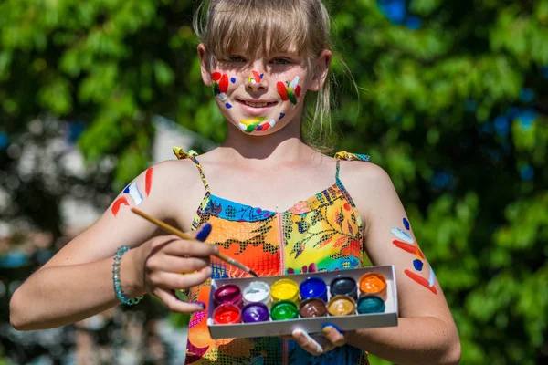 Chica linda alegre jugando con pinturas brillantes en el parque — Foto de Stock