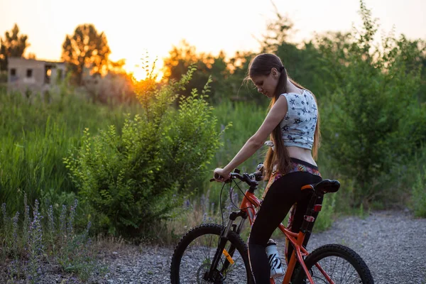 Attraktive sportliche Mädchen mit langen Haaren auf einem Fahrrad bei Sonnenuntergang — Stockfoto