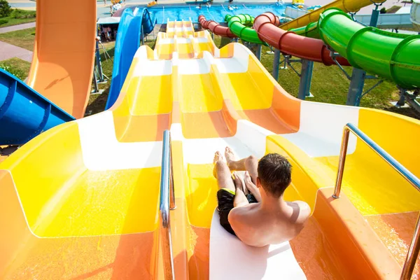 Vrolijke jongeman heeft plezier op vakantie op een dia in het waterpark — Stockfoto