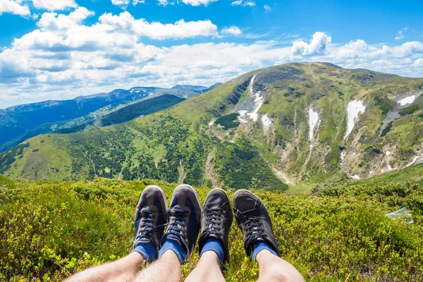 Coppia gambe sulla cima della collina guardando sulle montagne e bel cielo in giorno d'estate, vista in prima persona — Foto Stock