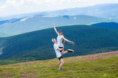 Mutlu bir genç adam tutan bir kadın yüksek zemin üzerine güzel bir gökyüzü ile dağlarda bir yaz günü