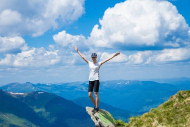 Genç kadın turist dağlar Cliff'in kenarında yükseltmek elinizi kaldırın