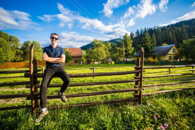Bir mutlu yakışıklı delikanlı el yapımı ahşap bir çit Bahçe üzerinde güneş gözlüğü