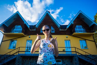 Happy young businesswoman in sunglasses bought a big home for her family clipart