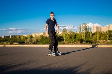 Mutlu genç adam paten günbatımı şehir Park