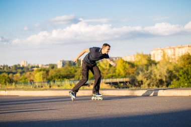 Mutlu genç adam paten günbatımı şehir Park