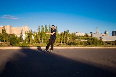 Mutlu genç adam paten günbatımı şehir Park