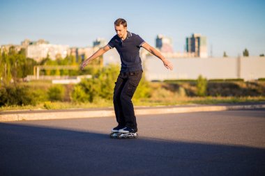Mutlu genç adam paten günbatımı şehir Park