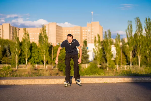 Mutlu genç adam paten günbatımı şehir Park
