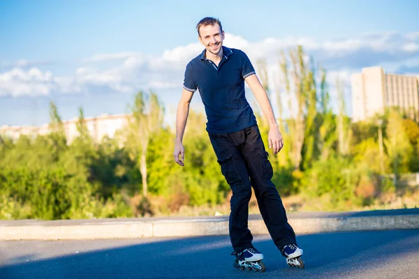 Mutlu genç adam paten günbatımı şehir Park