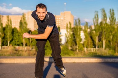 Mutlu genç adam paten günbatımı şehir Park