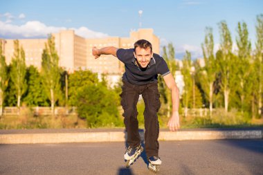 Mutlu genç adam paten günbatımı şehir Park