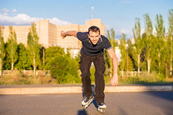 Mutlu genç adam paten günbatımı şehir Park