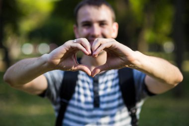 Genç adam ellerini aşk kalp şeklinde yapar.
