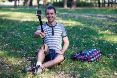 Çim ve bir eylem fotoğraf çekici selfie oturan genç adam