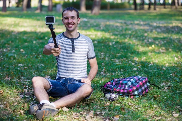 Çim ve bir eylem fotoğraf çekici selfie oturan genç adam