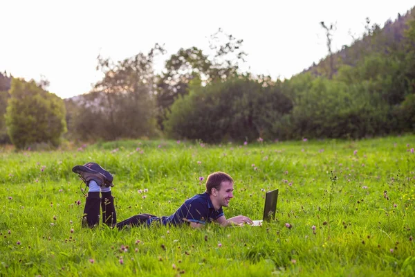 若い男にあるノート パソコンと緑の草の上 — ストック写真