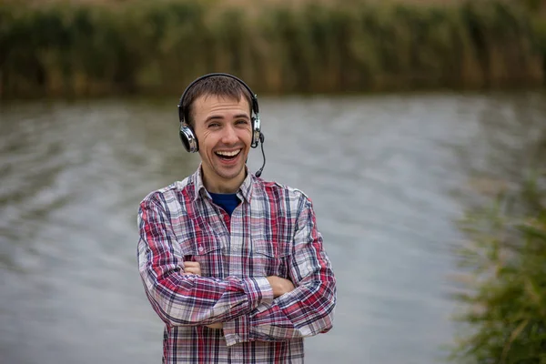 Portrett av en kjekk, smilende kundeserviceoperatør med hodetelefoner stående – stockfoto