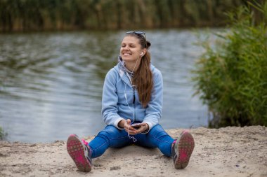 Mükemmel ruhları bir telefon ile genç gülümseyen kadın müzik dinliyor