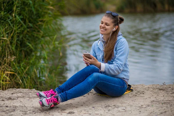 Genç gülümseyen kadın mükemmel ruhları ile bir telefon ve müzik dinler